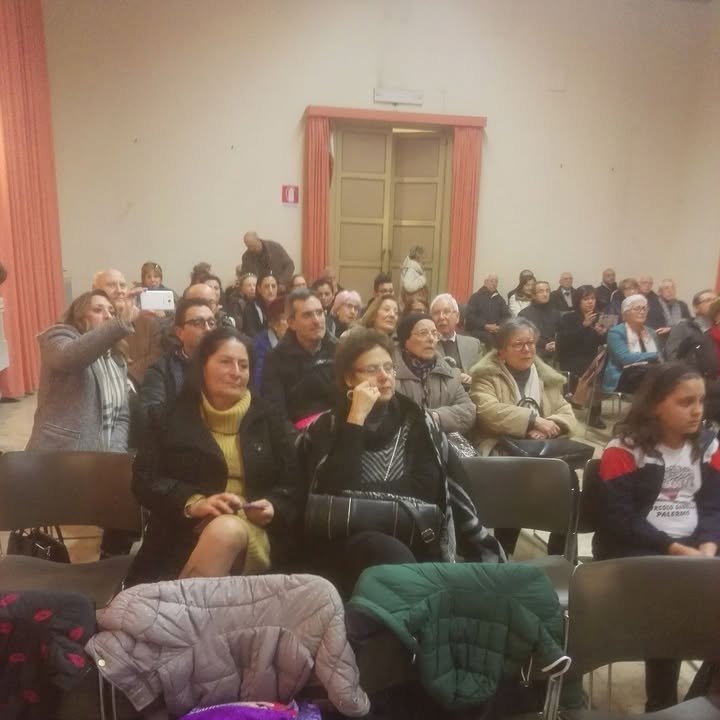 Una sala piena di persone sedute, a un incontro dell’associazione